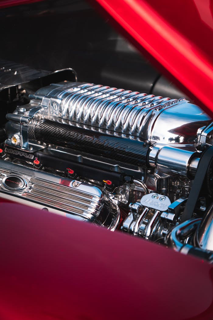 services-04 Detailed view of a shiny chrome engine in a vintage car, showcasing its restored parts.