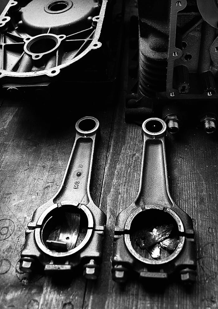 Monochrome close-up of metal engine parts on a wooden surface, showcasing industrial design.