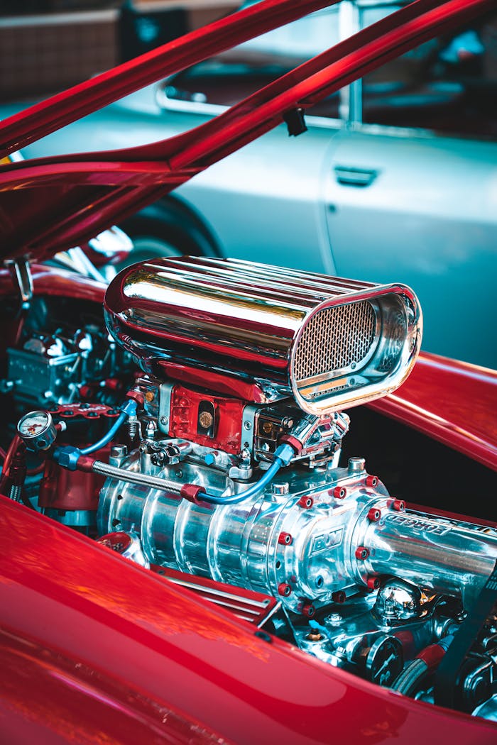 services-03 Detailed view of a chrome engine in a red classic car, showcasing engineering finesse.